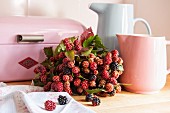 Bouquet of blackberries amongst jugs and bread bin in pastel shades