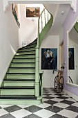 Wooden staircase painted pastel-green and black in period hallway with chequered floor and racing bike leaning against wall