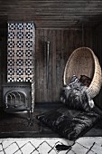 Wicker hanging chair in dark room with wood-burning stove