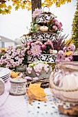 Herbstlich gedeckter Tisch mit einer Etagere voller Blumen