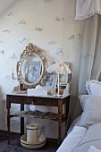Romantic arrangement of candlestick, ornate picture frame and table lamp with lace lampshade on bedside table