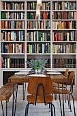 Square rustic wooden table and vintage chairs in front of bookcase
