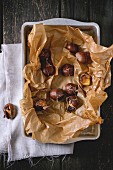 Peeled and unpeeled grilled edible chestnuts on a wooden table (seen from above)