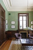 Grün getönter Wohnraum mit Stuckfries an Decke, im Vordergrund Jugendstil Pendelleuchte in Tiffany Stil, über Tisch