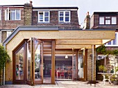 Modern wood and glass extension and terrace behind English terrace house
