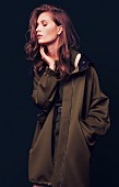 A young woman wearing an oversized, olive green coat