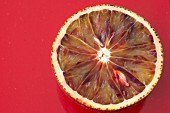 Half a blood orange on a red surface