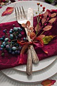 A place setting with antique cutlery decorated with autumnal leaves and berries