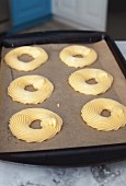 Piped choux pastry rings on a baking tray