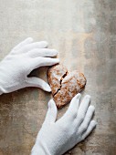 Gloved hands holding a heart-shaped gingerbread biscuit