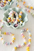 Colourful candy necklaces in and next to china bowls
