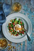 A poached egg on an asparagus and pea medley with bacon and croutons