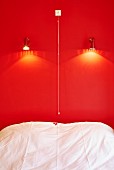 Bett vor roter Wand mit Beleuchtung