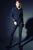 Junge Frau in dunkelblauer Bluse, Pulli und Röhrenhose