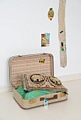 Offener Vintage Koffer mit Dekokissen, an Wand Holzbrett