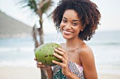 A young South American woman drinking coconut milk on a beach in Rio (Brazil)