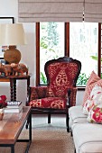 Antique armchair with ornate upholstery, plain sofa with floral scatter cushions and coffee table