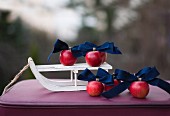 Red apples and dark blue ribbons on sledge ornament