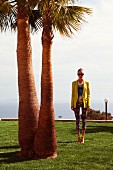 A young woman wearing a colourful shirt, capri trousers and a yellow blazer