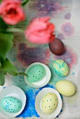 Painted Easter eggs in and next to paper cake cases