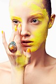 A young woman wearing a large ring apply yellow powder to her face