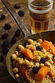 Vegan couscous with currants, chickpeas and carrots in a copper pan