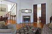 Armchair and sofa in living room with wide, open doorway with view of dining area and staircase