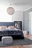 Elephant-patterned throw on bed, grey sparkly pouffe and striped rug in black and white bedroom with mixture of patterns