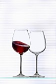 An empty wine glass and a glass of red wine