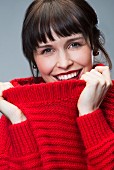 A dark-haired woman wearing a red knitted jumper