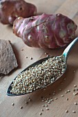 An arrangement of quinoa seeds on a silver spoon with Jerusalem artichokes
