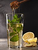 Mint tea in a glass with mint sprigs, lemon, ginger and honey