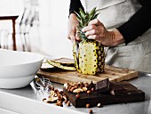 A man preparing a pineapple on a wooden board