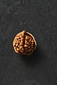 An opened walnuts on a grey surface (seen from above)