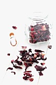 Dried hibiscus flowers in a jar and on a white cloth