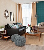 Black leather couch, retro glass coffee table and blue-grey crocheted pouffes in living room