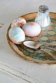 Variously painted Easter eggs, silver spoon and salt cellar on vintage tray