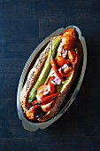 A hot dog with tomato salad and chilli peppers