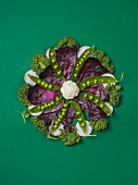 Various vegetables in a flower shape arranged on a green surface
