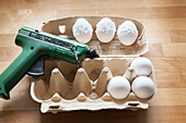 White eggs being decorated with a hot glue gun