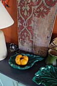 Gelbe Paprikaschote auf türkisgrüner Keramikschale vor Vintage Holzbrett