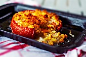A roasted tomato filled with breadcrumbs on a baking tray