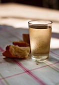 A glass of white wine and bread on a sunny table