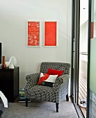 Vintage armchair with black and white patterned upholstery below modern artworks on wall