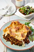 A portion of lasagne with salad