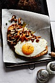 A fried egg on toast with chanterelle mushrooms