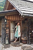 Junge Frau in winterlicher Kleidung steht in Eingang von Berghütte