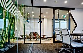 Classic office chairs in modern office in front of open door in steel and glass wall with view into lounge area