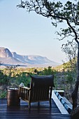 Wood-framed armchair and side table on terrace with view of wild landscape