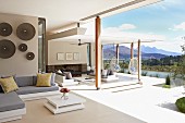 Eleganter Loggienbereich mit Sofa und modernem Bodentisch, Terrasse und Blick in bergige Flusslandschaft